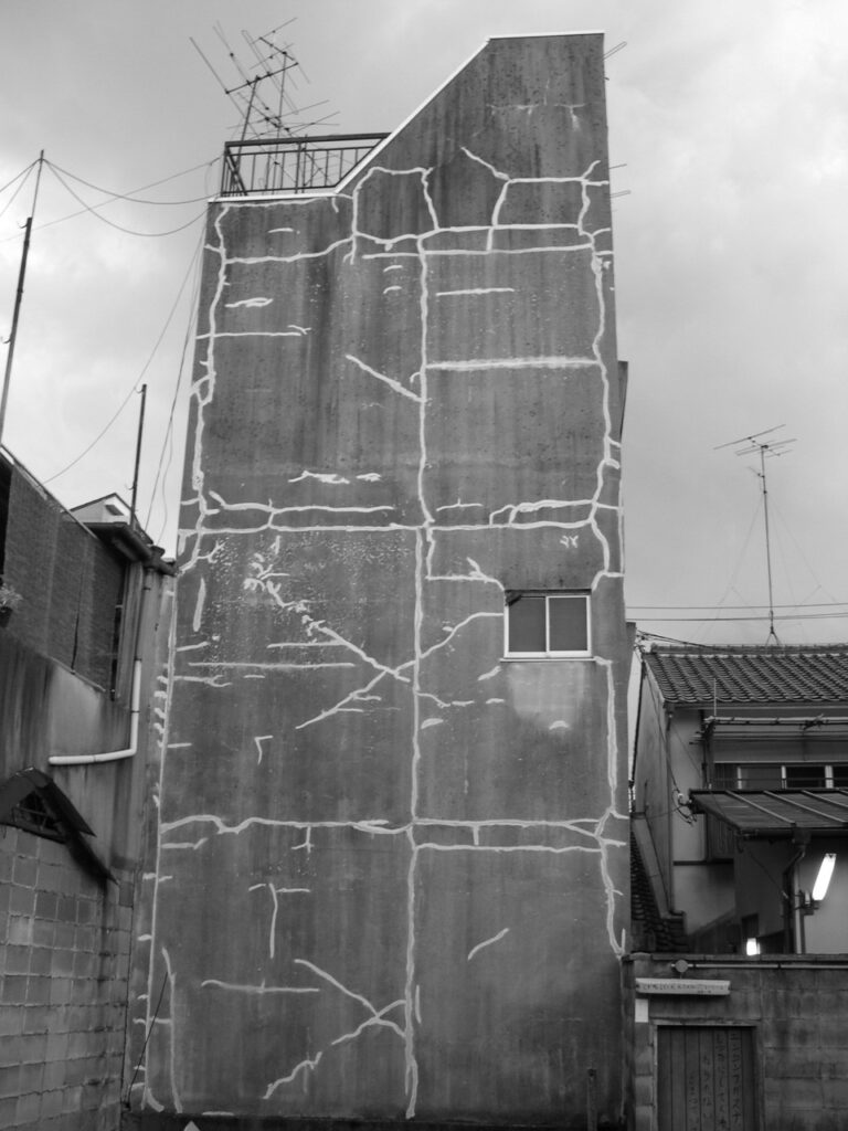 Mur extérieur d'un immeuble japonais avec les marques d'un ancien bâtiment attenant disparu.