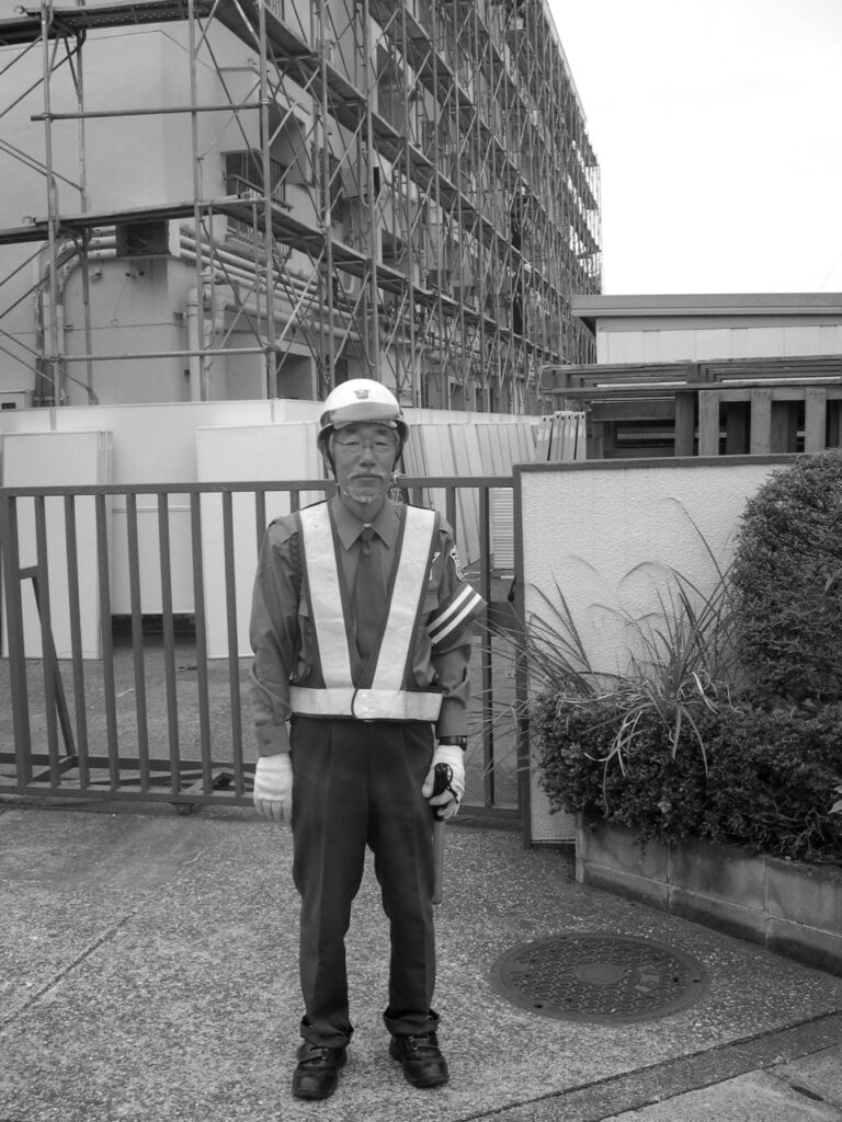 Portrait d'un gardien en uniforme devant un chantier au Japon.