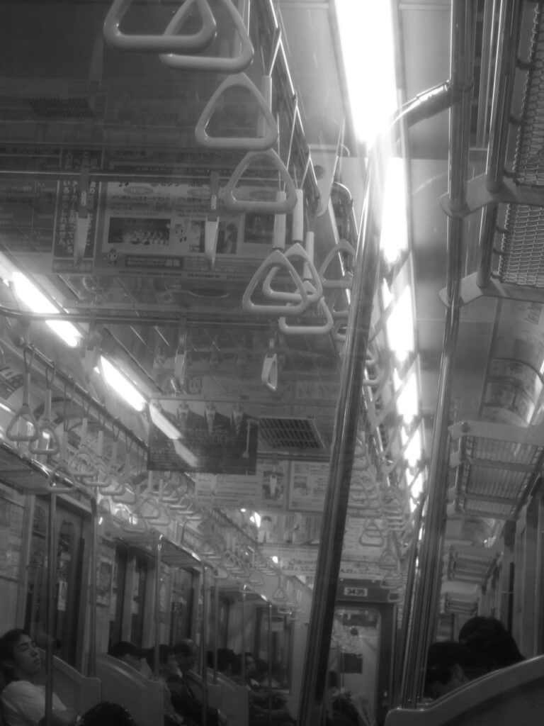 Intérieur d'une rame de métro japonaise en soirée avec ses lumières allumées.