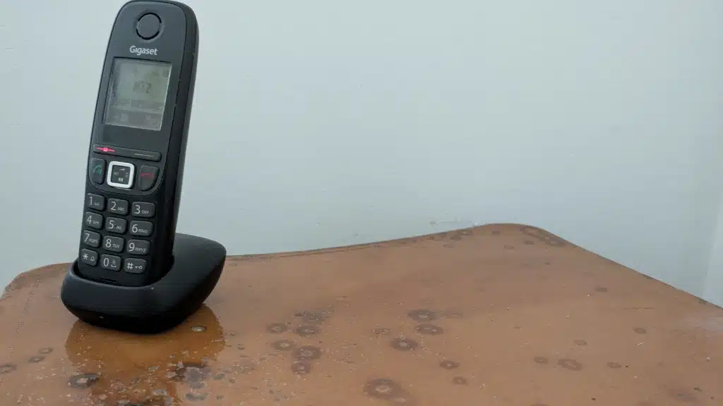 Un combiné de téléphone, seul. Mur blanc derrière.