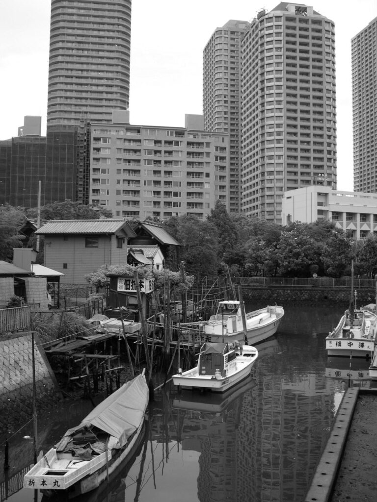 Petit port ancien à Tokyo au pied d'un complexe résidentiel aux immeubles imposants.