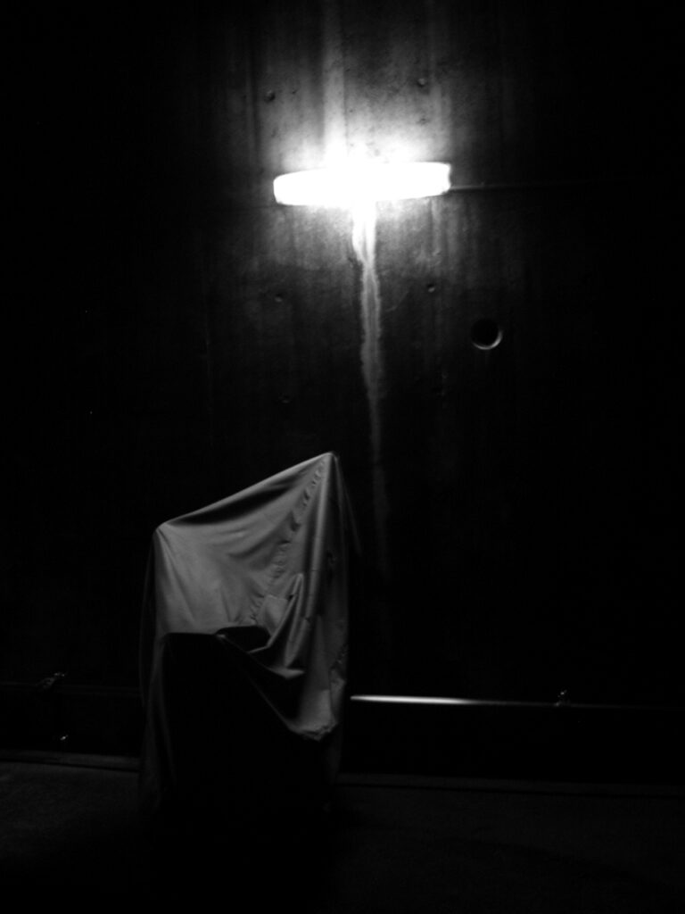 Moto bâchée sous un néon blafard, de nuit, dans un quartier japonais.