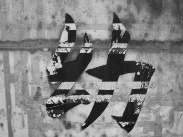Inscription du kanji « enfance » partiellement effacée sur la façade d'un bâtiment.