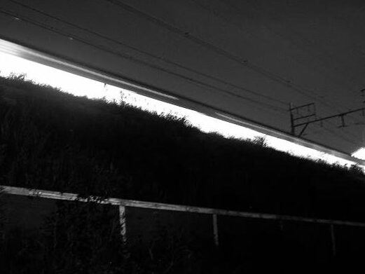 Passage d'un train de nuit au Japon, laissant un trait de lumière.