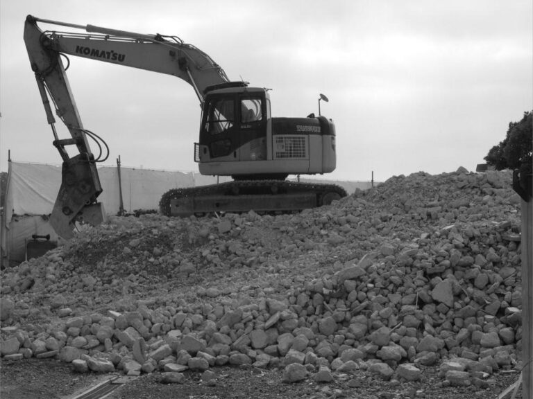 Engin de chantier à l'arrêt sur un amas de gravats.