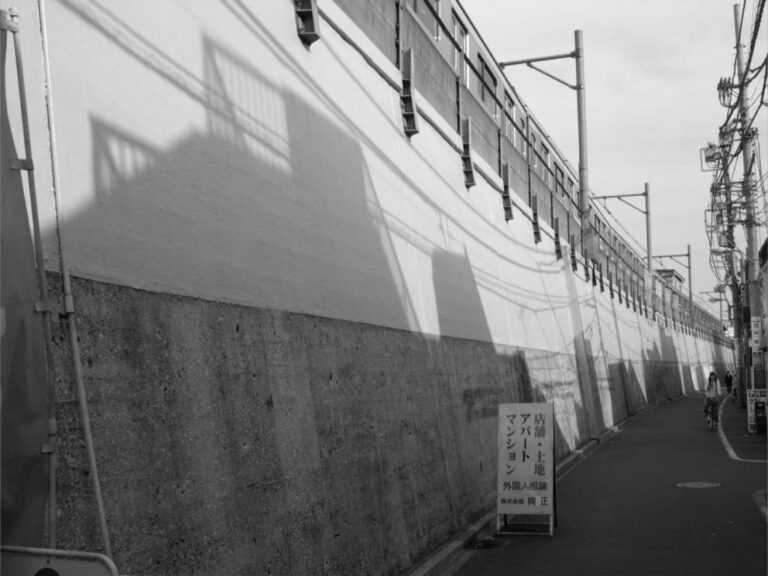 Ombres de bâtiments projetées sur le mur d'une voie ferrée au Japon.