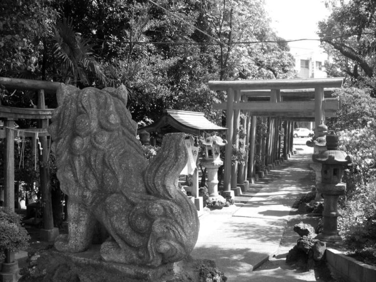 Statue d'un komainu vue de dos, montant la garde à l'entrée d'un sanctuaire japonais.